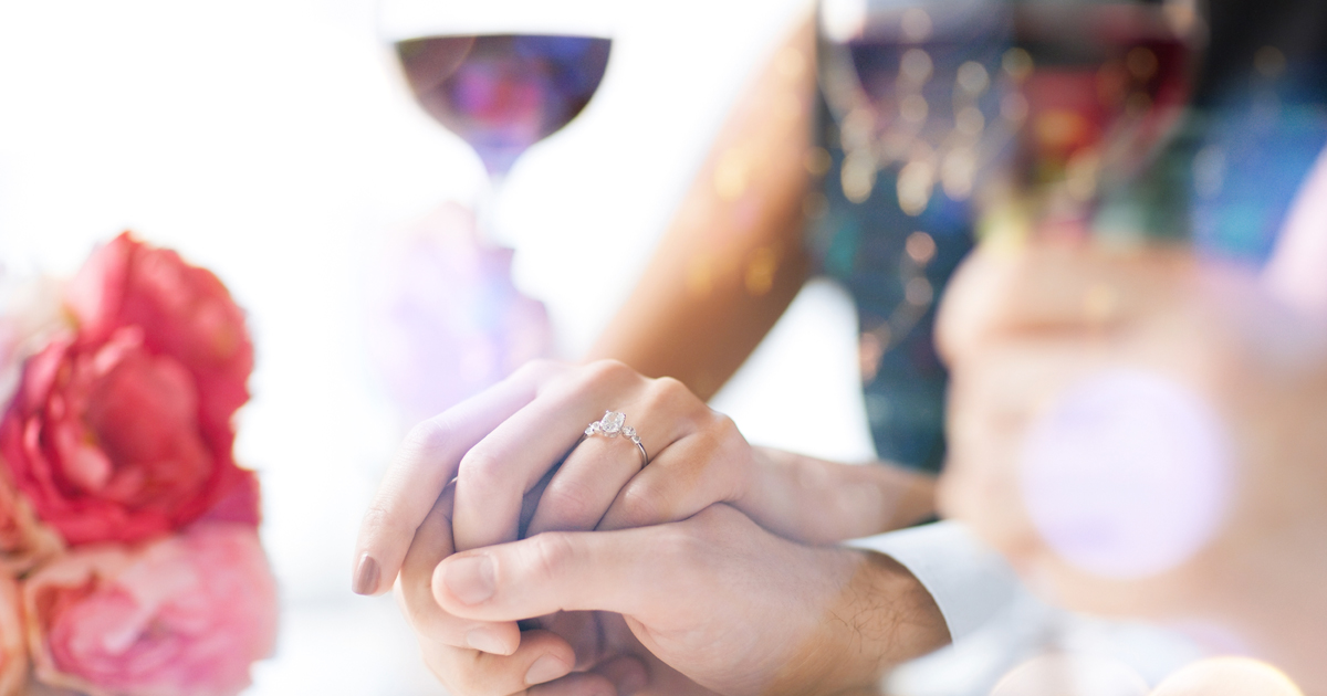 Woman wearing an engagement ring and holding hands with her fiance