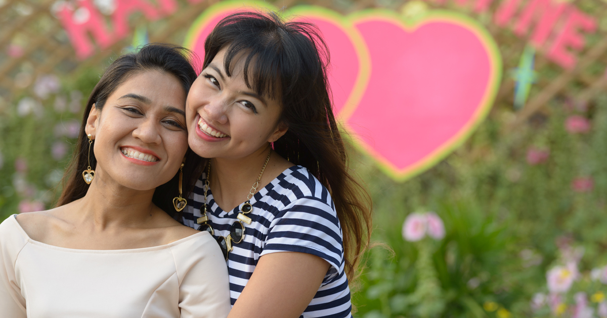 A couple smiling in front of two hearts