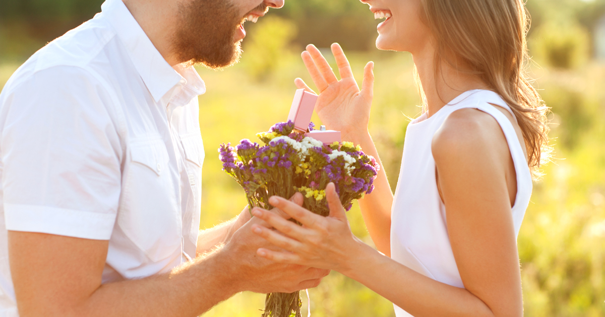 man with bunch of flowers and engagement ring proposing to a woman