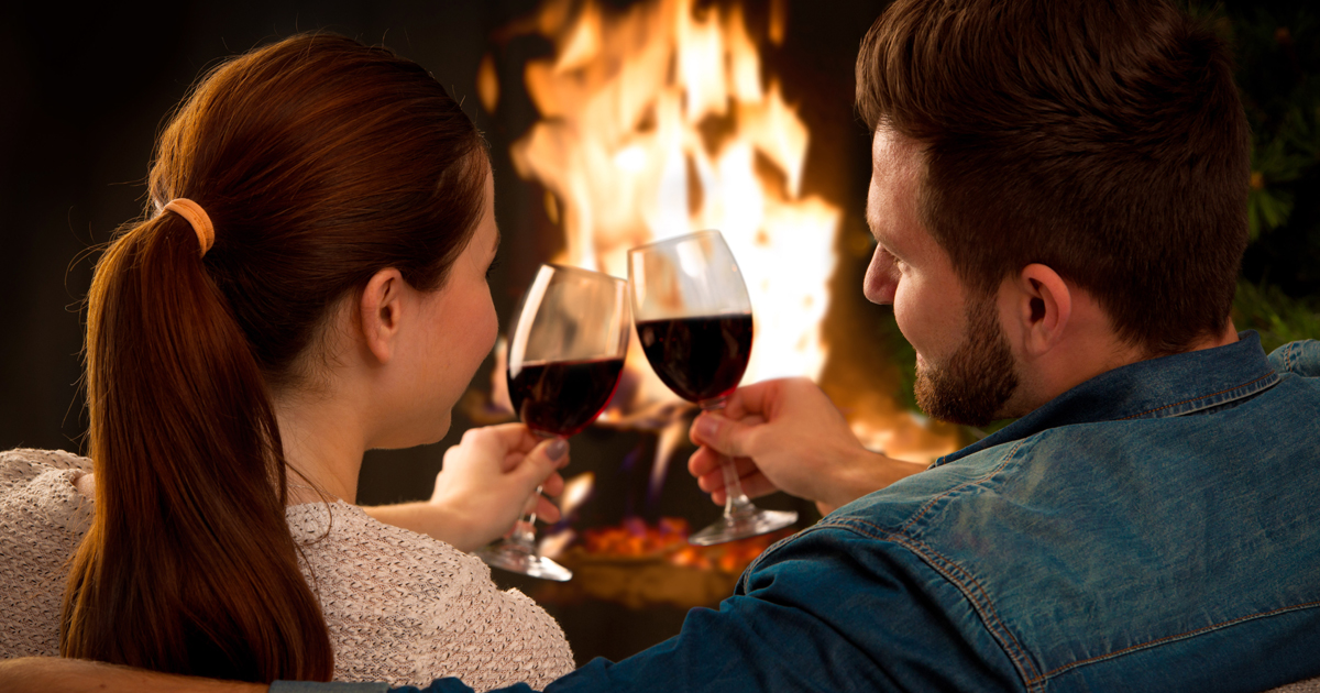 A couple drinking wine in front of a fire