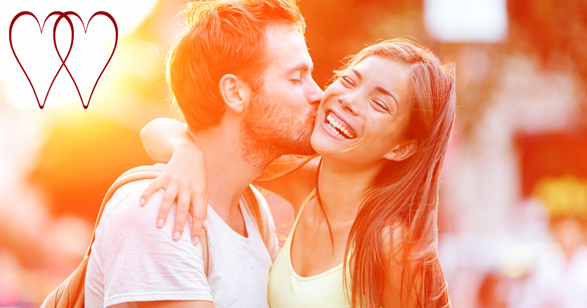 A man kissing his Valentine on the cheek as the sun sets