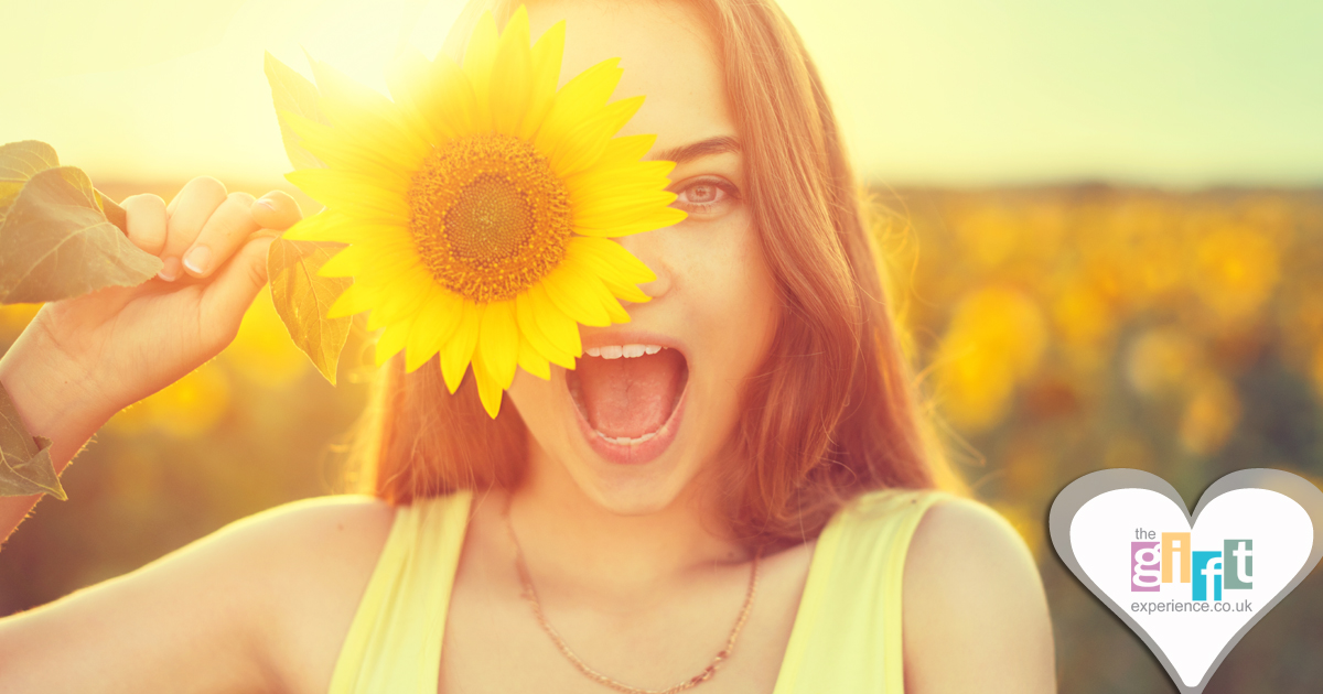 21 year old smiling and holding a sunflower