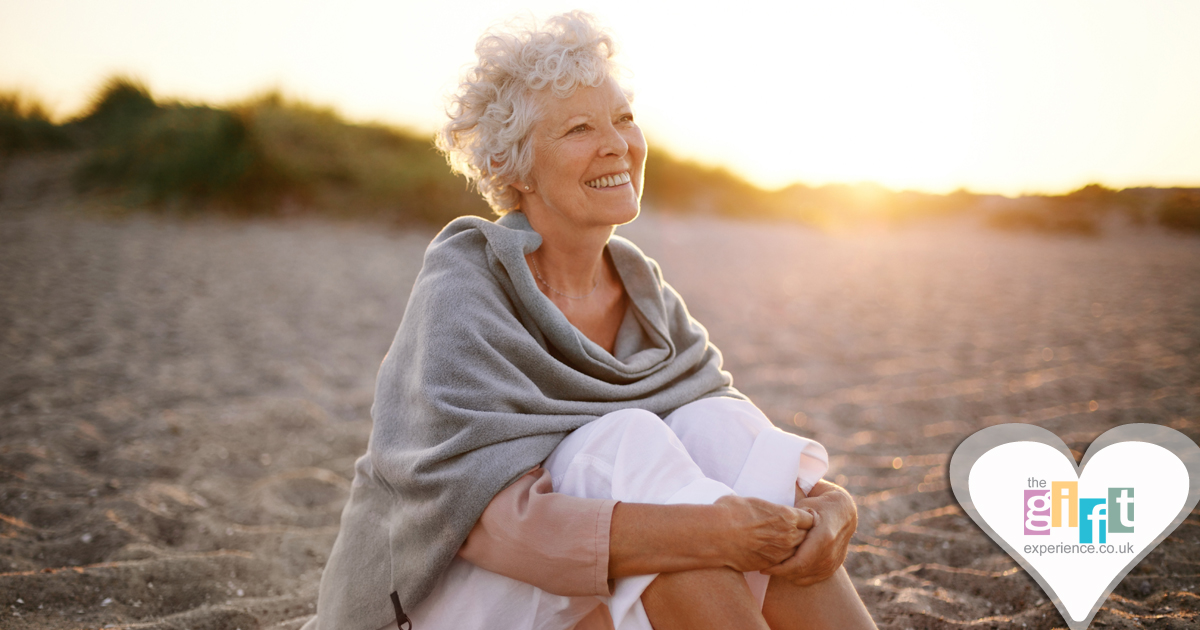 70 year old woman sitting on a beach in the sun