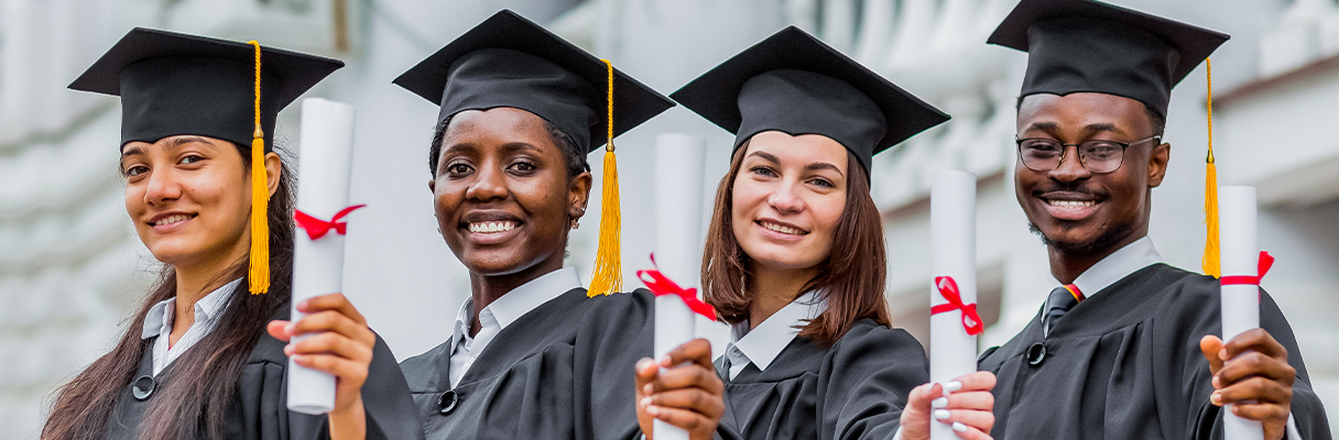 Group of happy graduates in caps and gowns holding diplomas celebrating graduation day