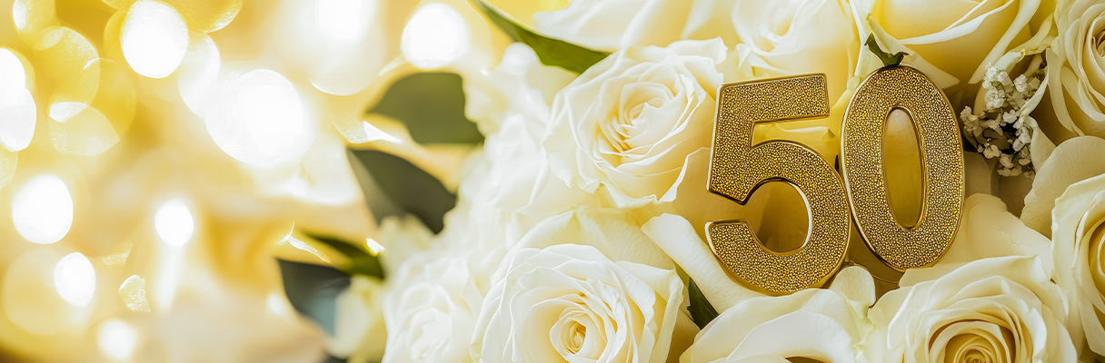 Golden “50” decoration nestled in a bouquet of cream roses, perfect for 50th wedding anniversary celebrations