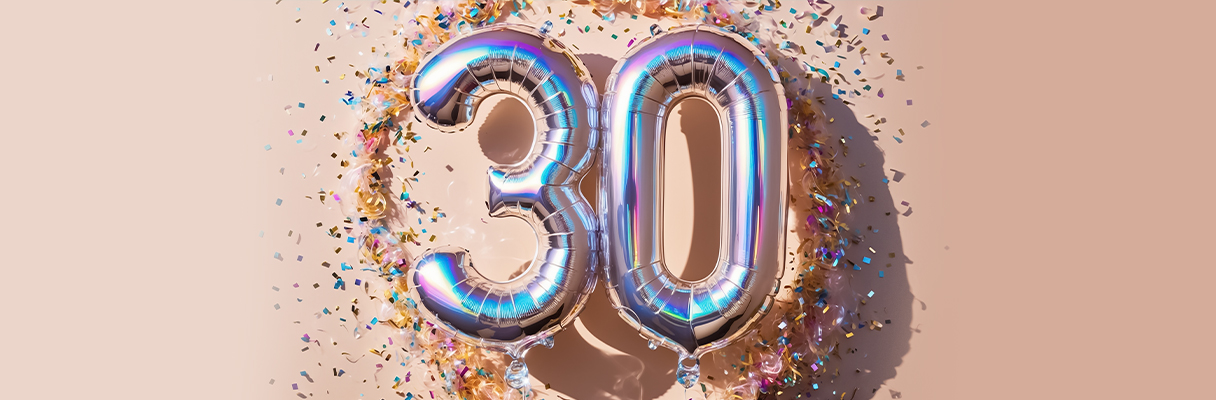Silver “30” balloons surrounded by colourful confetti on peach background for 30th wedding anniversary