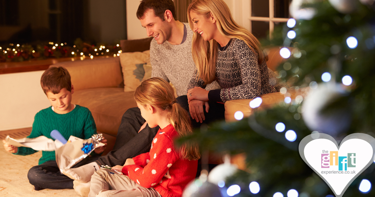 a family opening gifts in front of the tree at Christmas a family opening gifts in front of the tree at Christmas