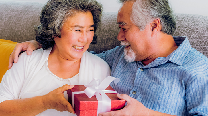 Senior couple smiling and exchanging a thoughtful anniversary gift, celebrating love and lifelong memories