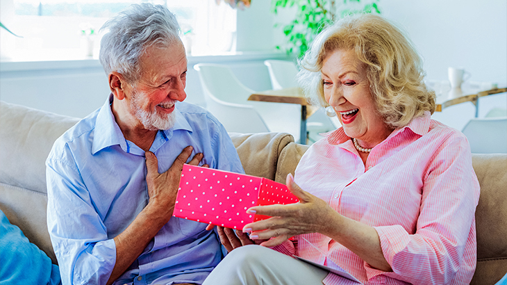 Senior couple exchanging gifts on their 50th wedding anniversary golden celebration