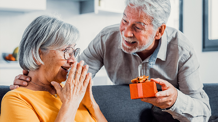 Senior couple smiling and exchanging a thoughtful anniversary gift, celebrating love and lifelong memories