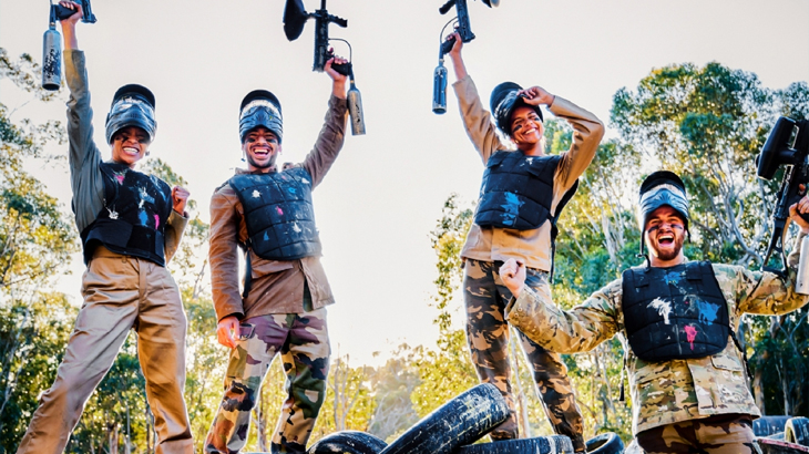 Paintball players celebrating victory in full gear, outdoor team paintball experience, adrenaline-filled group activity
