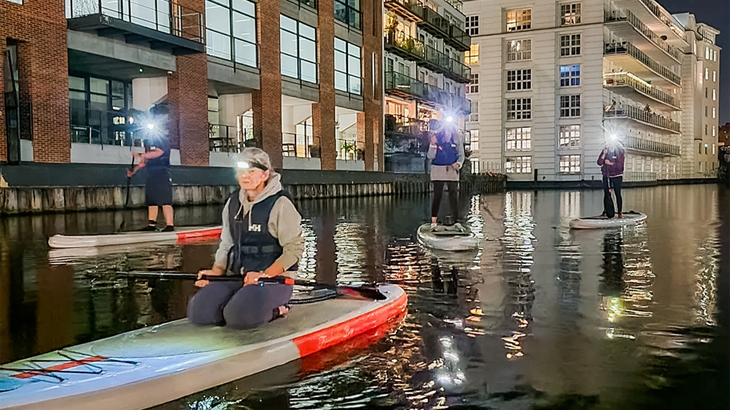 Group paddleboarding on Regent's Canal in London at night, peaceful and sentimental outdoor experience, unique London water activity