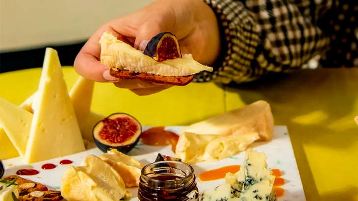 Person holding cheese from a tasting board at Funky Cheese Shoreditch, artisan cheese experience in London