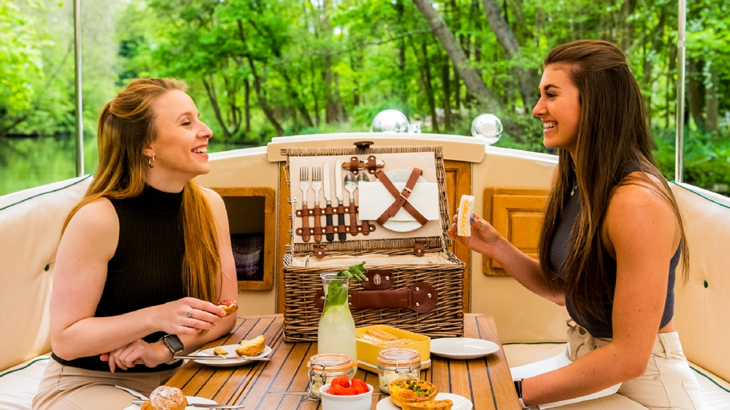 Two women enjoying a luxury picnic boat cruise for two, perfect for a romantic anniversary celebration