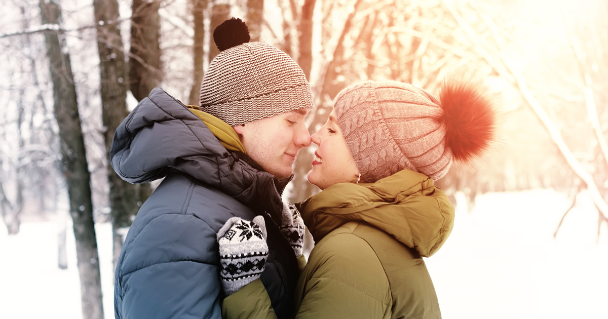 couple kissing in the forest while it snows