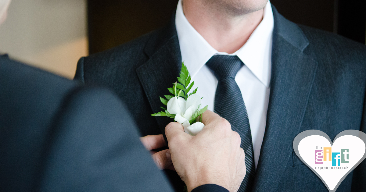 The Groom helps the Best Man place his boutonniere The Groom helps the Best Man place his boutonniere